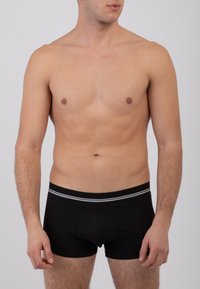 Boxer in cotone nero con una texture liscia, caratterizzati da un design aderente e una vita a strisce bianche a contrasto.