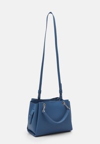 Modrá kožená kabelka s texturovaným povrchem, dvojitými uchy a dlouhým nastavitelným popruhem. Obsahuje kovové detaily a boční kapsu.