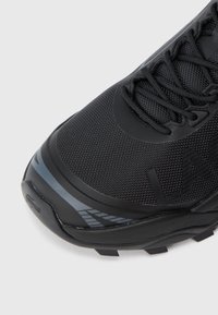 Crne sportske tenisice s teksturiranim gornjim dijelom od tkanine i gumenim potplatom. Sadrže elegantne sive akcentne detalje i zaobljen dizajn prstiju. S vezanjem sprijeda.