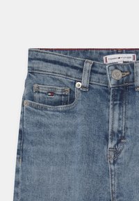 Tommy Hilfiger spijkerbroek in lichtblauw met een klassiek vijf-pocket ontwerp, metalen knoopsluiting en logo patch op de tailleband.