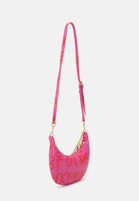Bolso de hombro rosa hecho de material brillante, con texto naranja llamativo. Acentuado con una correa de cadena y una correa de hombro ajustable.