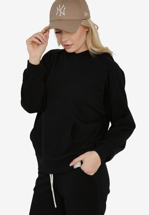 Czarna bluza z kapturem, z przednią kieszenią, o miękkiej fakturze i ściągaczami. Uzupełniona jasnobrązową czapką z białym logo.