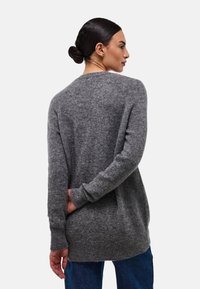 Pull oversized gris en maille douce, avec des manches longues et un col rond, possédant un ourlet arrière plus long.