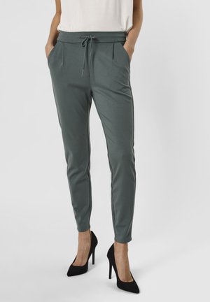 Grønne, tapered joggebukser med snøring i midjen, sidelommer og kontrasterende svarte sidestreker, laget av et glatt, mykt stoff.