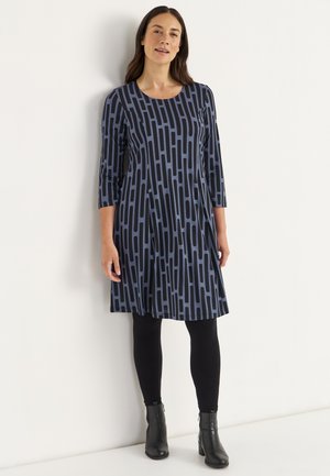 Blaues Kleid mit schwarzem vertikalem Streifenmuster, runder Ausschnitt, Dreiviertelärmel, knielang, kombiniert mit schwarzen Leggings und Stiefeletten.