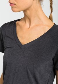 Mörkgrå V-ringad t-shirt tillverkad av mjukt, lätt material. Har en avslappnad passform och korta ärmar, med synliga sömsdetaljer.