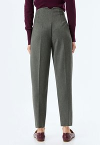 High-waisted, grey tailored trousers with a textured fabric, featuring front pleats and a v-shaped back waistline.