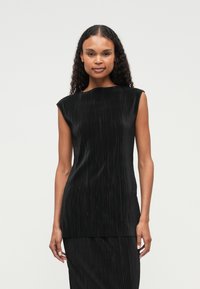 Μαύρη αμάνικη μπλούζα με πλεκτή υφή, ψηλό λαιμό και ίσια γραμμή. Λείος ύφασμα με ελάχιστο σχέδιο και χωρίς ορατά εξαρτήματα.