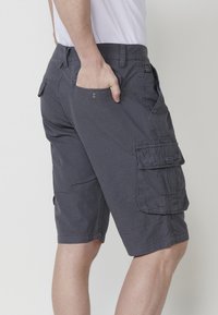 Grijze cargoshorts van lichtgewicht stof, met meerdere zakken, subtiele textuur en een regular fit die net boven de knie eindigt.