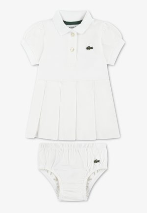 Vestito bianco in cotone con colletto polo, maniche a sbuffo e gonna plissettata. Include pantaloncini bianchi abbinati con elastico in vita e logo.