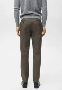 Pantalones marrones de tela suave con dos bolsillos traseros, costuras sutiles y un ajuste entallado, combinados con un suéter gris texturizado.