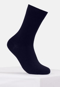 Calcetín de algodón negro con una textura suave, de longitud media hasta la pantorrilla y punta reforzada. Presenta un puño acanalado para un ajuste y soporte adecuados.