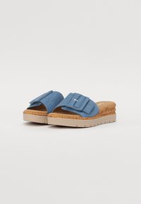 Blue slip-on sandals with a fabric upper, wide top strap, and decorative buckle. Cork-like outsole with a textured bottom for grip.