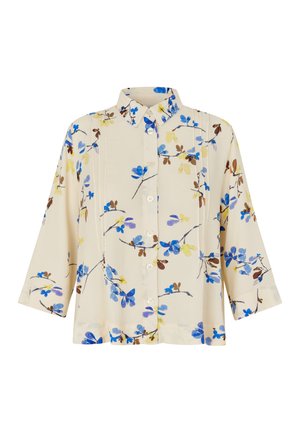 Chemise à boutons à motif floral, fabriquée en tissu léger, avec des motifs de fleurs bleues, jaunes et marron sur un fond crème, manches trois-quarts.