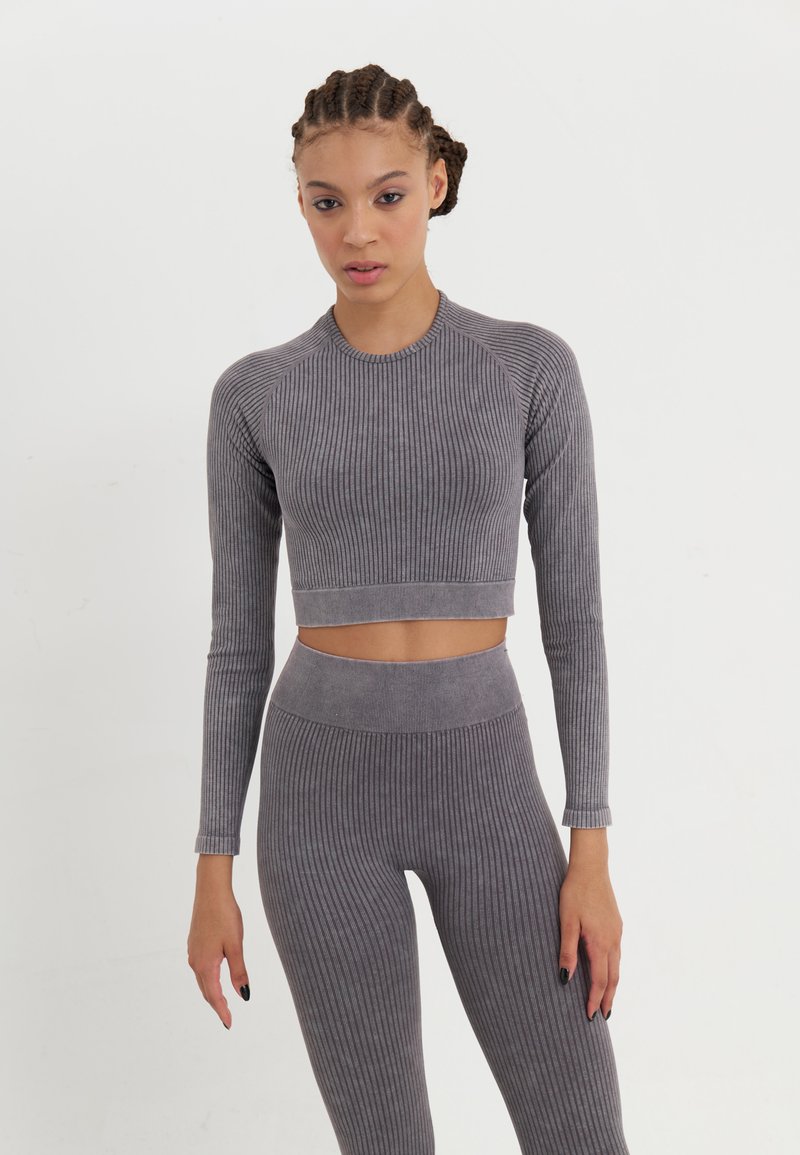 Sivi rebrasti dugih rukava crop top i visoko strukirane tajice, napravljene od teksturiranog materijala. Odjeća ima uski kroj i bešavne rubove.