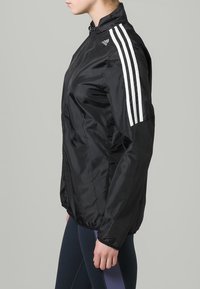 Black windbreaker jacket with a zip front, made of sleek, lightweight material. Features three white stripes on each shoulder.