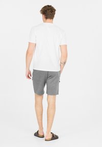 Witte T-shirt met korte mouwen, grijze textuur shorts en bruine sandalen. De shorts hebben zijzakken en een casual pasvorm.