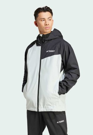 Lichte, waterdichte jas met een ritssluiting aan de voorkant, een zwarte capuchon en grijze lichaamspanelen. Voorzien van een merkembleem op de borst en zakken.