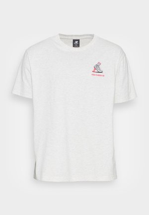 Weißes T-Shirt mit kurzen Ärmeln von New Balance, mit einem kleinen pinken und grauen Sneaker-Graphic und dem Text "new balance" auf der linken Brust.