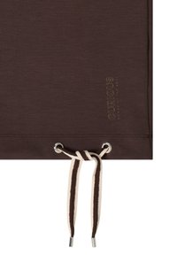 Tissu marron foncé avec ourlet cousu, cordon bicolore noué à travers des œillets argentés, et petit texte "CURIOUS NOMAD OF THE SOUL" en or.