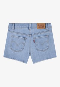 Jasnoniebieskie szorty z denimu z postrzępionym wykończeniem, dwoma tylnymi kieszeniami oraz skórzaną metką na pasku, na której widnieją informacje o marce.