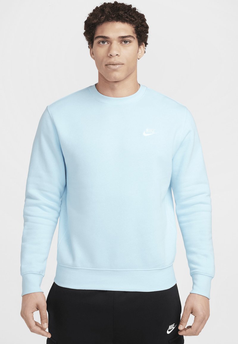 Sudadera Nike de color azul claro con cuello redondo, puños y dobladillo acanalados. Presenta un pequeño logo blanco de Nike en el lado izquierdo del pecho.