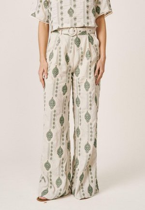 Pantalones anchos color crema con estampados de hojas verdes, combinados con un top corto a juego y un cinturón color crema con hebilla redonda.