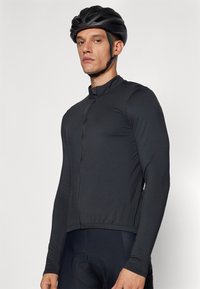 Svart langermet sykkeldrakt med høy krage, glidelås foran og tettsittende design. Jevn tekstur og lett stoff for komfort.