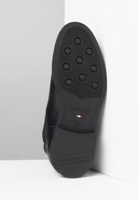 Suola di scarpa nera in gomma con modelli di trazione circolari, logo in rilievo e testo che indica la produzione italiana, taglia 42.