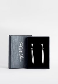 Silverhänge i en svart sammetsfodrad låda. Örhängena har avlånga, avsmalnande former med en glansig yta; lådan har en texturerad grå utsida.