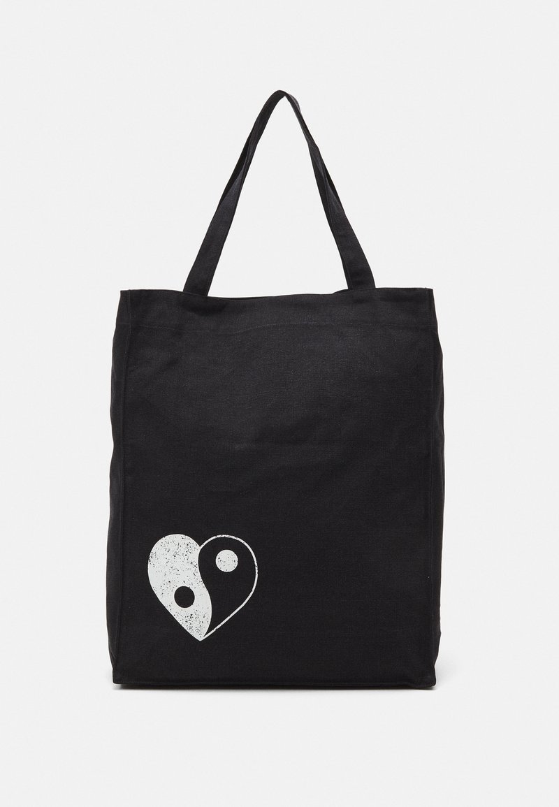 Black tote bag made of canvas, featuring a white yin-yang heart graphic. Two sturdy handles for easy carrying. Simple rectangular design.