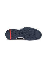 Suola di una scarpa con una superficie in gomma blu scuro testurizzata, dotata di scanalature verticali e orizzontali, con una striscia di accento rossa.