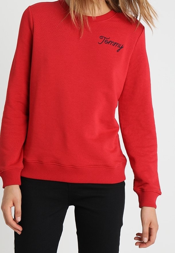 Sweatshirt rouge en coton, avec un col rond, des manches longues, et un petit détail brodé "Tommy" en marine sur la poitrine.