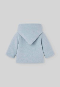 Veste tricotée bleu clair avec une grande capuche, présentant un motif texturé et des manches courtes, conçue pour le confort et la chaleur.