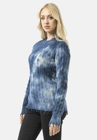 Pull en maille bleu avec un design texturé, ourlet effiloché et encolure scallopée. Fabriqué en matériau doux avec un effet dégradé.