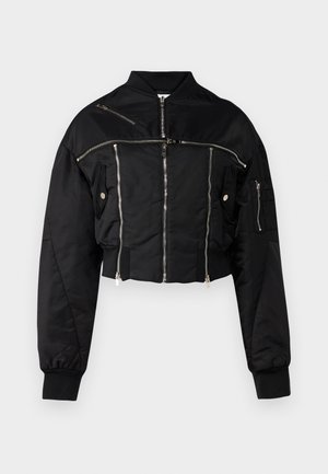 Juoda trumpa bomber tipo striukė, pagaminta iš lygaus audinio. Turi sidabrinius užtrauktukus, guminę apykaklę ir kelias užtrauktukais uždaromas kišenes.