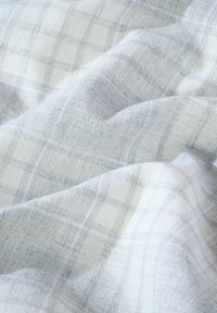 Puha, világosszürke és fehér kockás szövet, finom kockás mintával, gyengéd redőkben és textúrában közelről bemutatva.