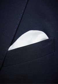 Marinskjorta med detalj av en vikt vit näsduk i bröstfickan, som visar upp en texturerad tyg och rena linjer.