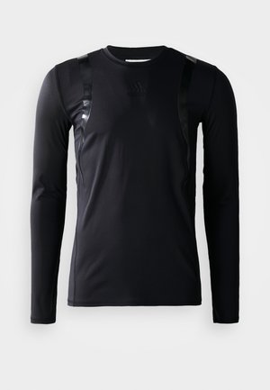Schwarzes, langärmliges Sportshirt aus glattem, dehnbarem Stoff. Verfügt über glänzende schwarze Akzente an den Schultern und ein Adidas-Logo auf der Brust.