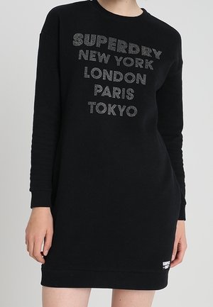 Abito felpa nero con maniche lunghe, con testo argentato: "SUPERDRY", "NEW YORK", "LONDRA", "PARIGI", "TOKYO". Tessuto morbido, vestibilità comoda.