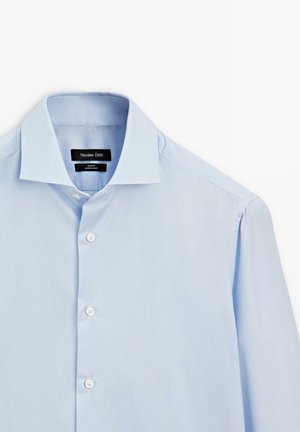 Světle modrá košile na knoflíky s pevným límcem, bílými knoflíky a jemnou pruhovanou texturou. Štítek viditelný uvnitř límce.