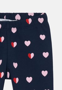 Navy Leggings mit einem elastischen Bund, der mit einem Muster aus pinken und roten Herzen in verschiedenen Größen versehen ist. Weiches Baumwollmaterial.