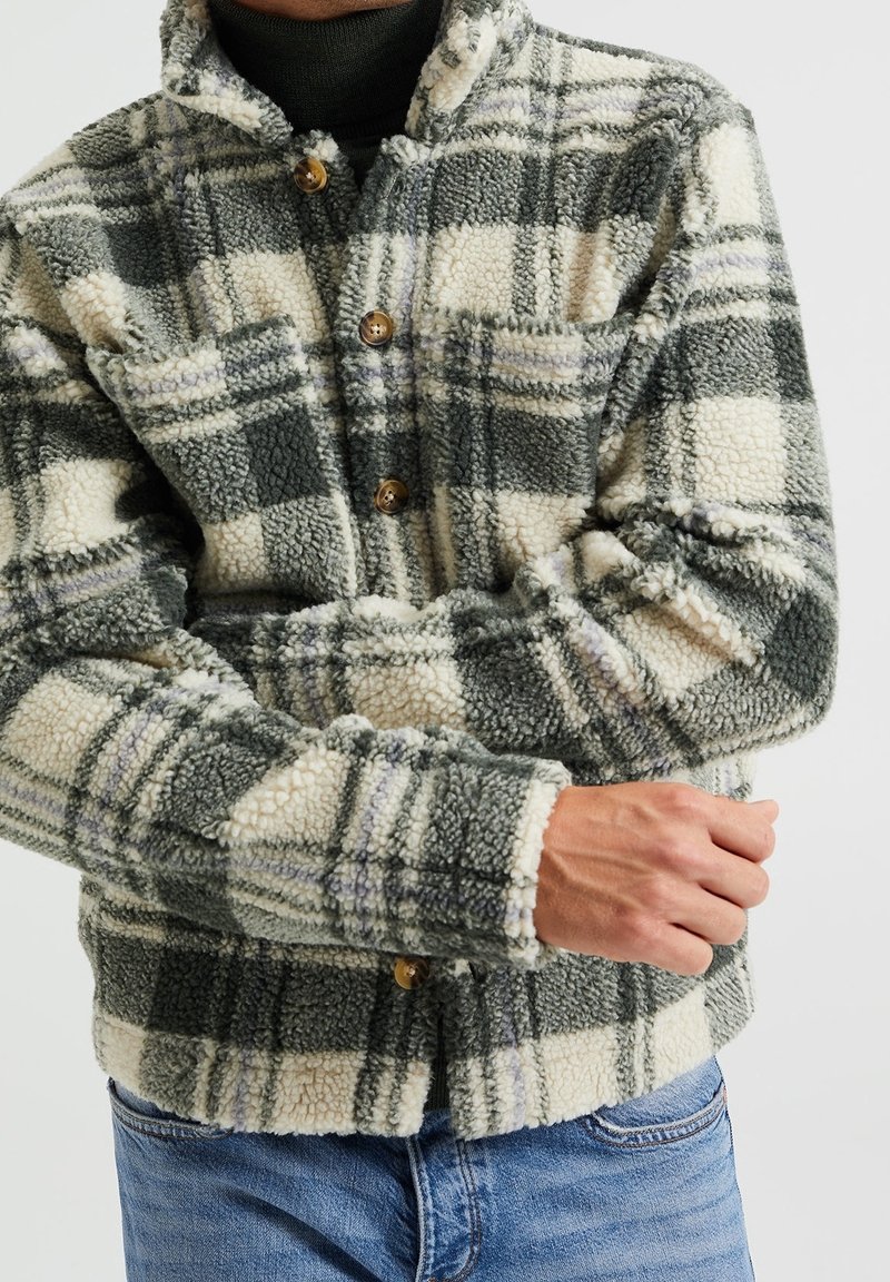 Vihreä- ja kermanvalkoinen ruudullinen fleecetakkipaita, jossa napilliset kiinnitykset, kaulus ja pehmeästi viimeistelty tekstuuri.