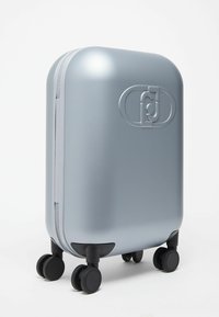 Valise rigide compacte de couleur argent avec quatre roues doubles noires pivotantes et un logo en relief sur le panneau avant.