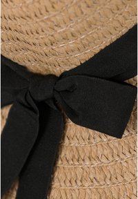 Woven straw hat featuring a wide, textured black fabric bow accent, highlighting natural tones and intricate braided patterns.