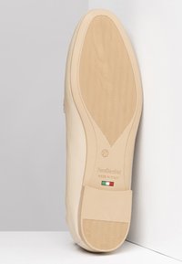 Semelle de chaussure NeroGiardini beige, dessus en cuir lisse, semelle extérieure en caoutchouc flexible avec motif en vagues, détail en texte italien et drapeau, taille 37.