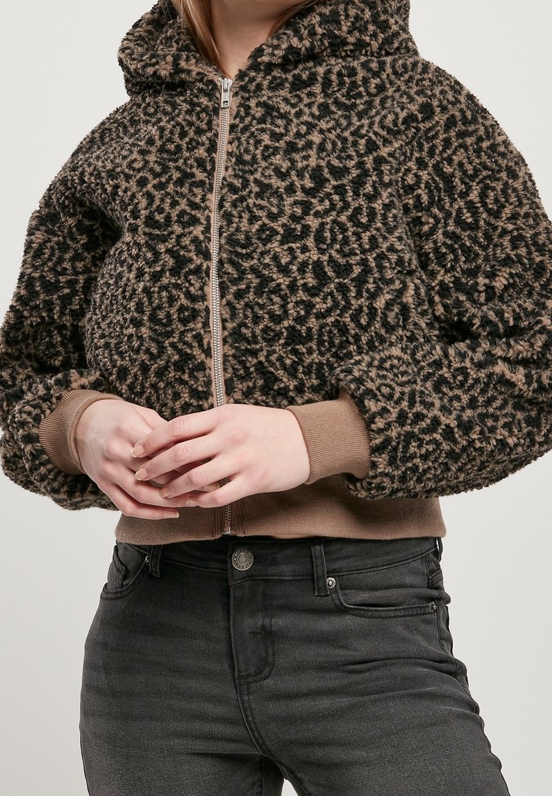 Sudadera con cremallera de forro polar con un patrón de leopardo negro y marrón, puños y dobladillo acanalados. Presenta una capucha y un tejido suave y texturizado.