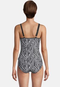 Zwart-wit gestreept badpak met zebra-patroon, voorzien van verstelbare banden en een aangesloten silhouet, gemaakt van een gladde, elastische stof.