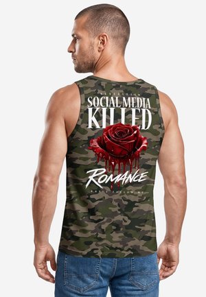 Mann, der ein Tarn-Top mit einer roten tropfenden Rose und dem Text "Social media killed romance" auf dem Rücken trägt.