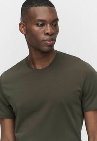 Olivenfarvet T-shirt med korte ærmer og rund halsudskæring, lavet af blødt bomuld, med en tætsiddende pasform og glat tekstur.